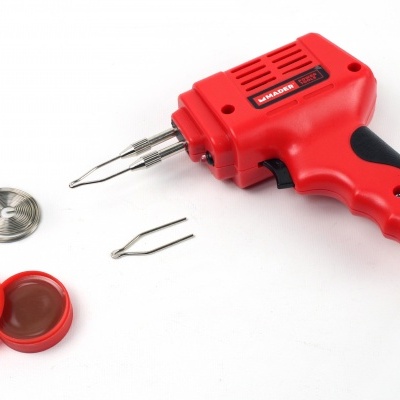 Ferro de soldar vermelho com acessórios sobre fundo branco