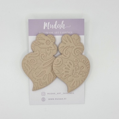 Brincos artesanais em tom bege com padrão floral montados num cartão de apresentação lilás e branco