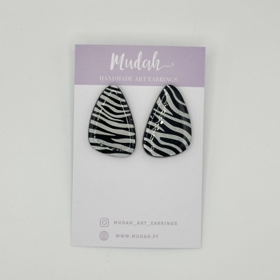 Brincos artesanais com padrão zebra preto e branco em cartão de apresentação lilás e branco