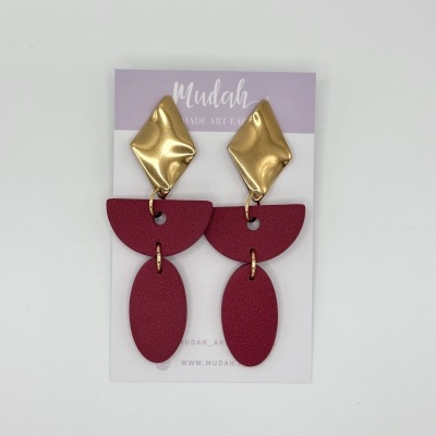 Brincos dourados com peças geométricas vinhos em cartão lilás