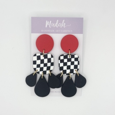 Brincos artesanais com círculos vermelhos, quadrados em padrão de tabuleiro e pingentes pretos