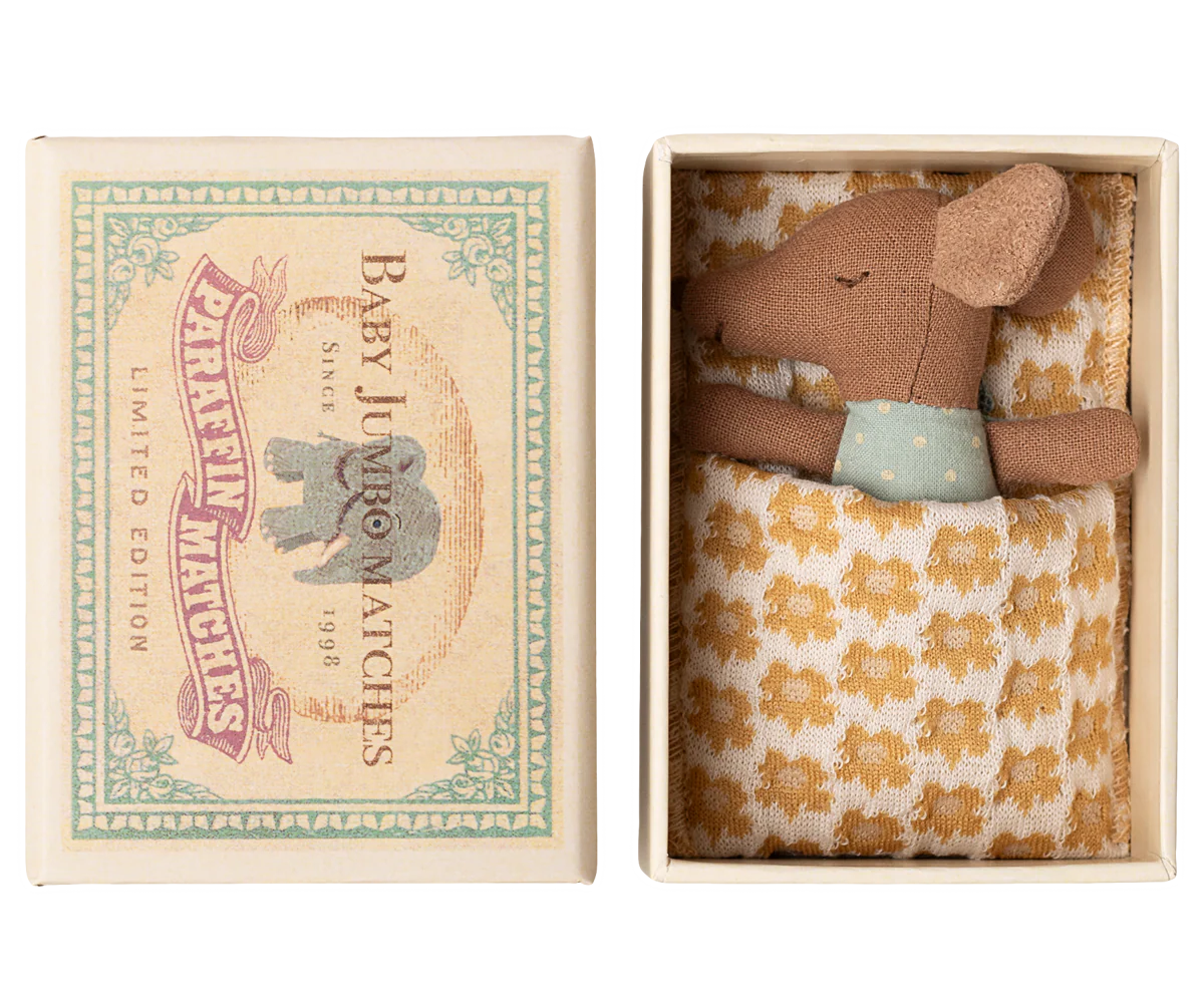 Caixa decorativa de fósforos com brinquedo de rato de tecido na cama.