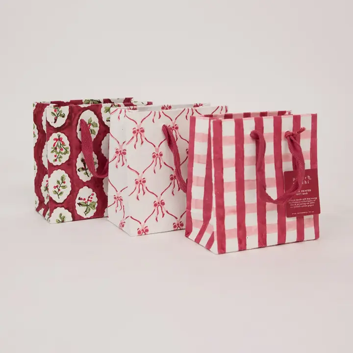 Sacos de papel para presente com padrões festivos em vermelho e branco e alças de corda vermelha