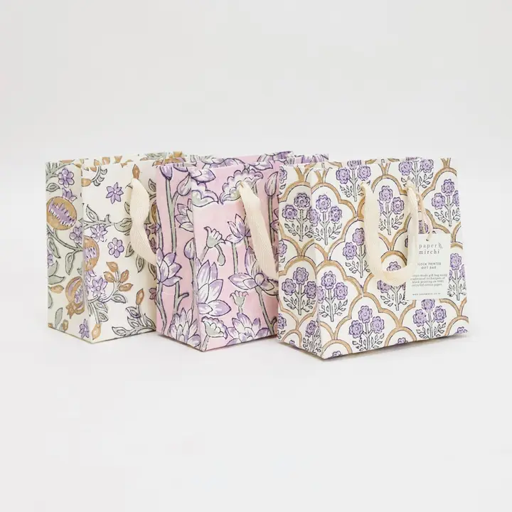 Três sacos de tecido com estampas florais e alças de corda