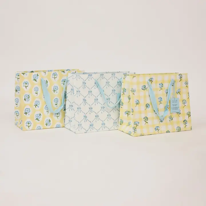 Três bolsas têxteis coloridas com padrões florais e alças azuis