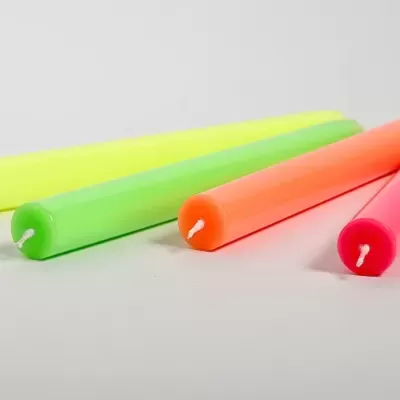 Quatro velas cilíndricas neon em amarelo, verde, laranja e rosa com pavios brancos