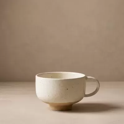 Caneca de cerâmica creme com manchas castanhas e asa arredondada