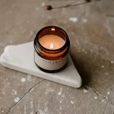Vela aromática em frasco âmbar sobre mármore branco