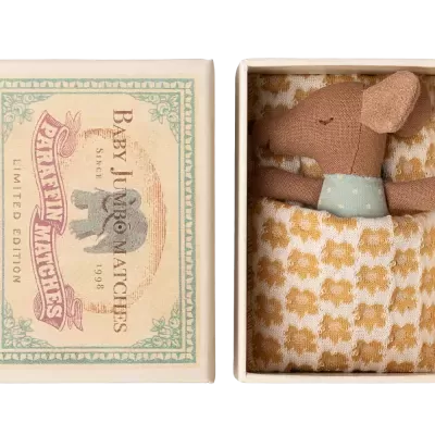 Caixa decorativa de fósforos com brinquedo de rato de tecido na cama.