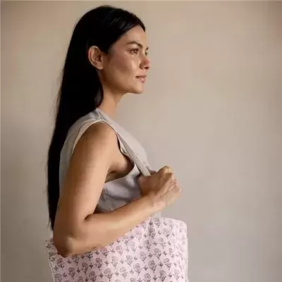Saco rosa com padrão floral preto ao ombro de mulher com blusa cinza