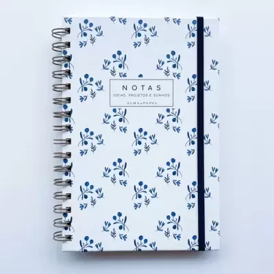 Caderno de notas com padrão azul e branco, espiral e elástico azul