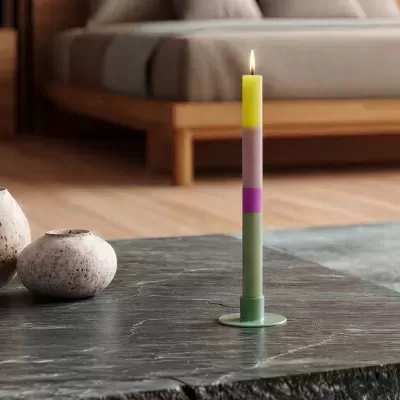 Vela de cera multicolor em castiçal verde numa mesa de pedra escura