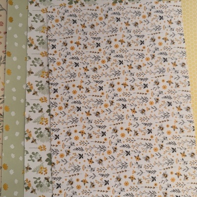 Folhas de papel decorativas com padrões florais e abelhas em tons amarelo, verde e bege