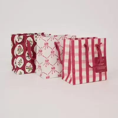 Sacos de papel para presente com padrões festivos em vermelho e branco e alças de corda vermelha