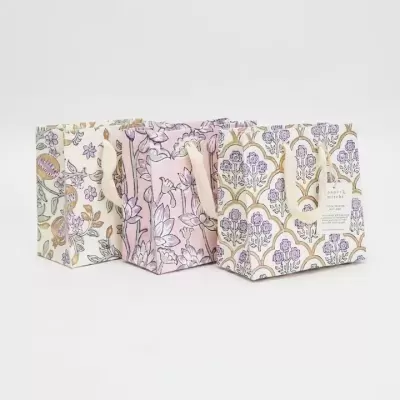 Três sacos de tecido com estampas florais e alças de corda