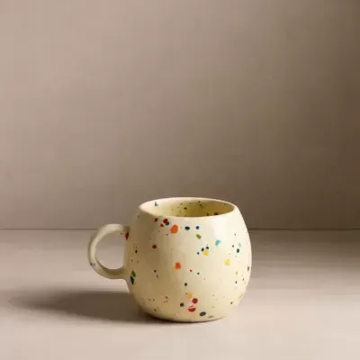 Caneca redonda creme com manchas coloridas e asa