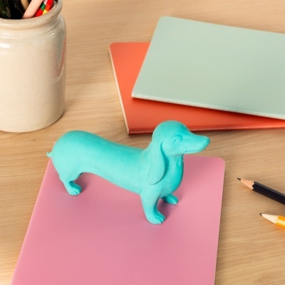 Estátua decorativa de cão azul com cadernos coloridos e lápis numa mesa