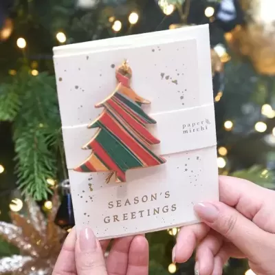 Cartão de Natal com árvore decorativa colorida e texto Seasons Greetings