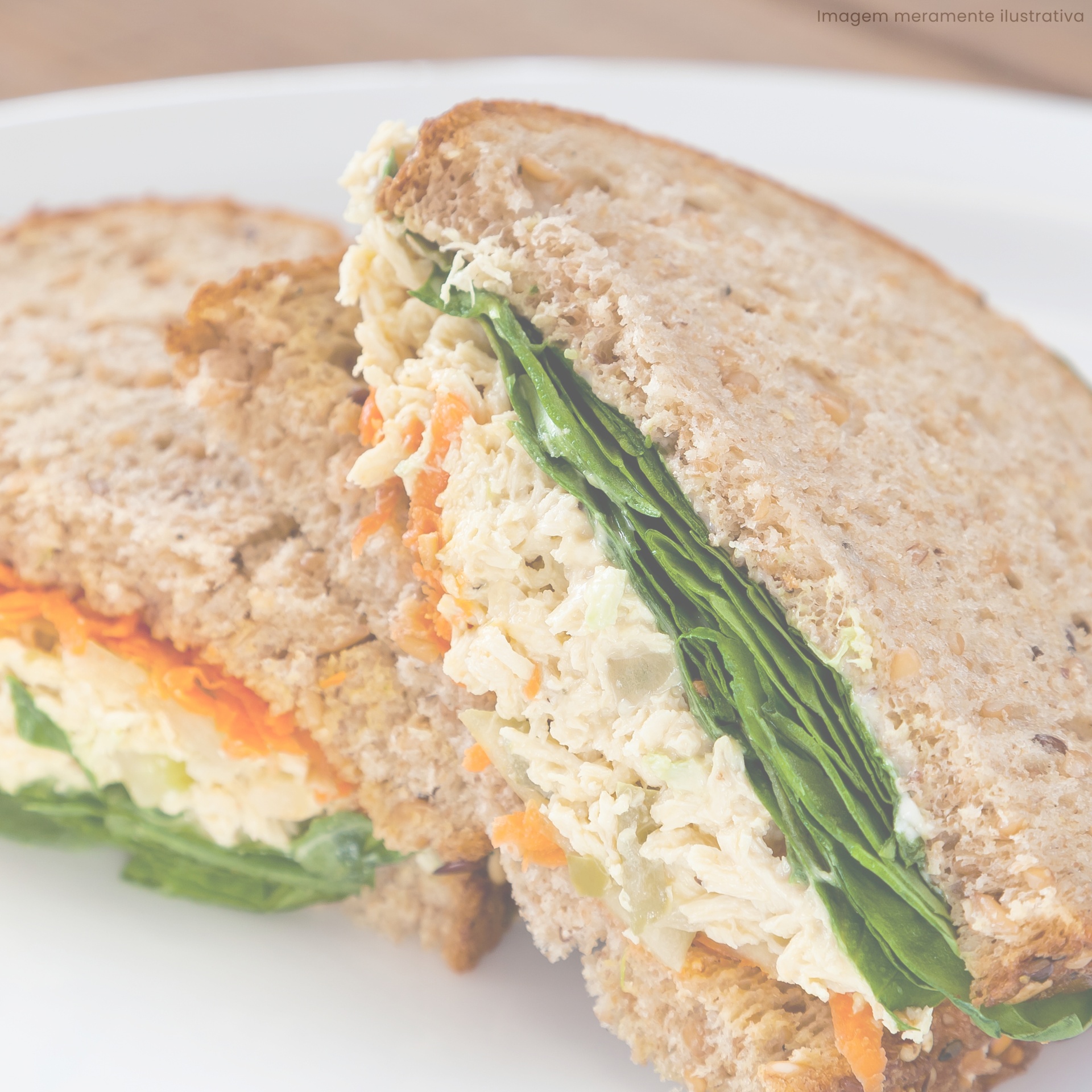 Sanduíche integral com recheio de folhas verdes e cenoura num prato branco