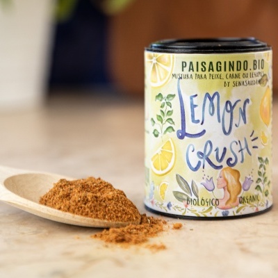 Lata colorida de mistura em pó Lemon Crush com colher de madeira e pó ao lado sobre uma superfície clara