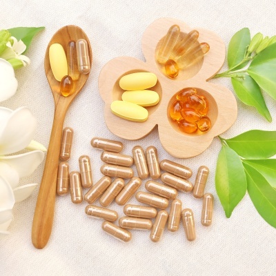 Cápsulas e comprimidos de suplementos alimentares, colher de madeira, folhas verdes