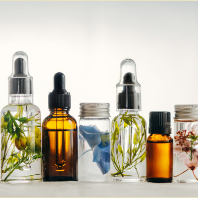 Frascos pequenos com plantas e óleos essenciais em fundo branco