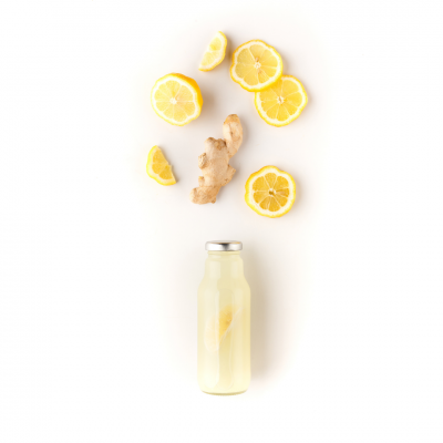 Garrafa com bebida clara, gengibre e rodelas de limão sobre fundo branco
