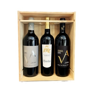 Caixa de madeira com três garrafas de vinho tinto, rótulos cinza, branco e preto com letras 'A V'