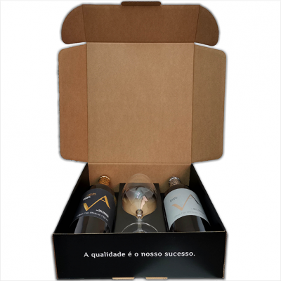 Caixa preta aberta com duas garrafas de vinho VÁ e uma taça de vidro no meio