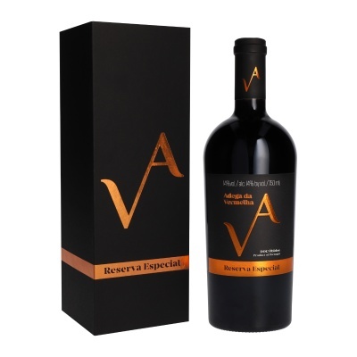 Garrafa de vinho tinto com rótulo preto e laranja ao lado de caixa preta alta com detalhes laranja