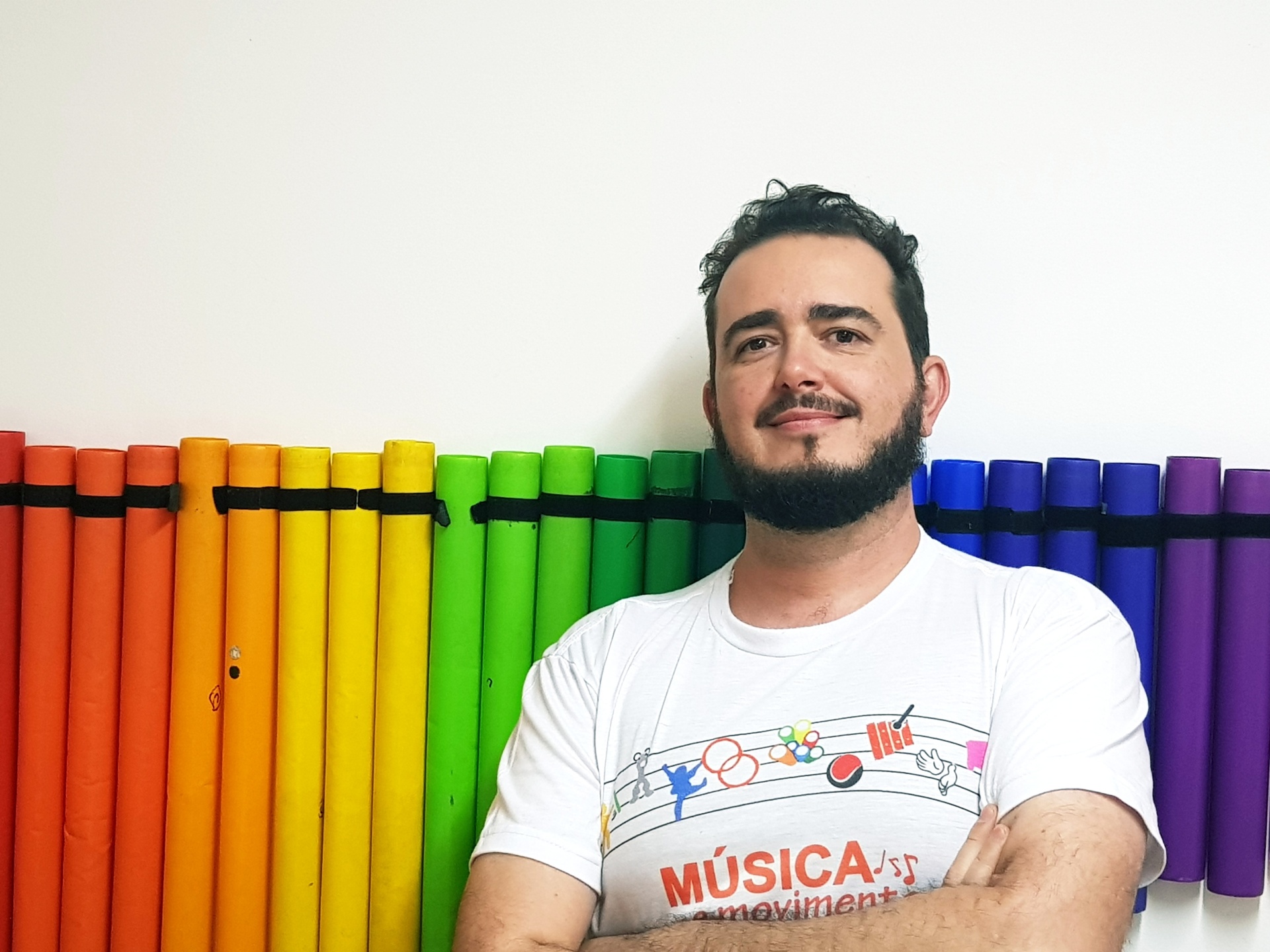 Música 3D - Tordesillas, España - 28 noviembre Homem com t-shirt branca com texto e símbolos musicais junto a tubos coloridos organizados na parede