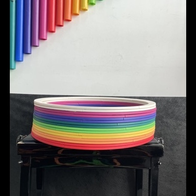 Arcos coloridos empilhados em banco preto com tubos coloridos na parede