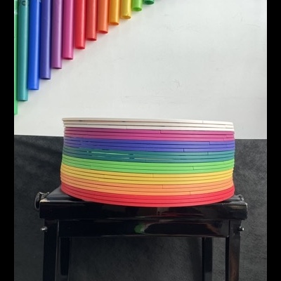 Paus de chuva coloridos em camadas sobre banco com tubos coloridos pendurados na parede