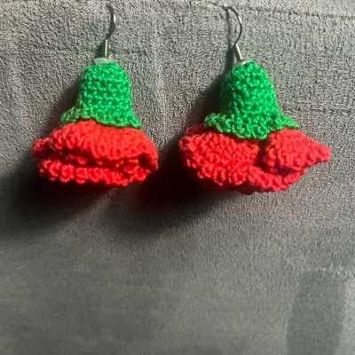 Brincos de croché em forma de flores vermelho e verde com fundo cinza.