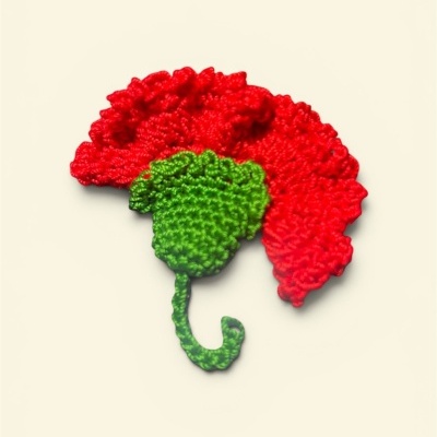 Flor vermelha e verde de crochê sobre fundo bege