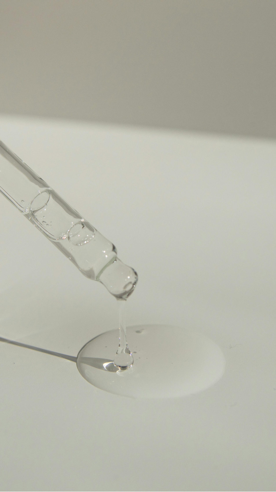 Pipeta a deixar cair um líquido transparente numa superfície branca