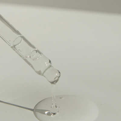 Pipeta a deixar cair um líquido transparente numa superfície branca
