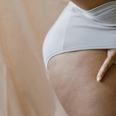 Roupa interior branca em algodão com mão sobre coxa