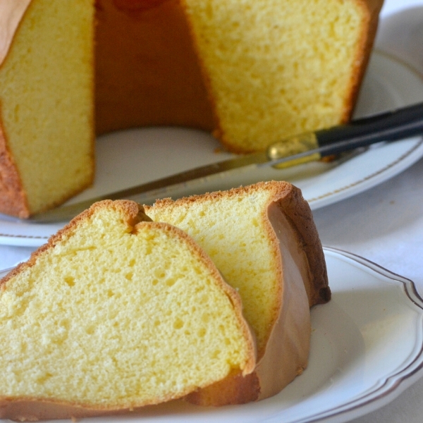 Preparado Pão Ló,500gr Bolo amarelo fatiado servido em prato branco com faca ao lado