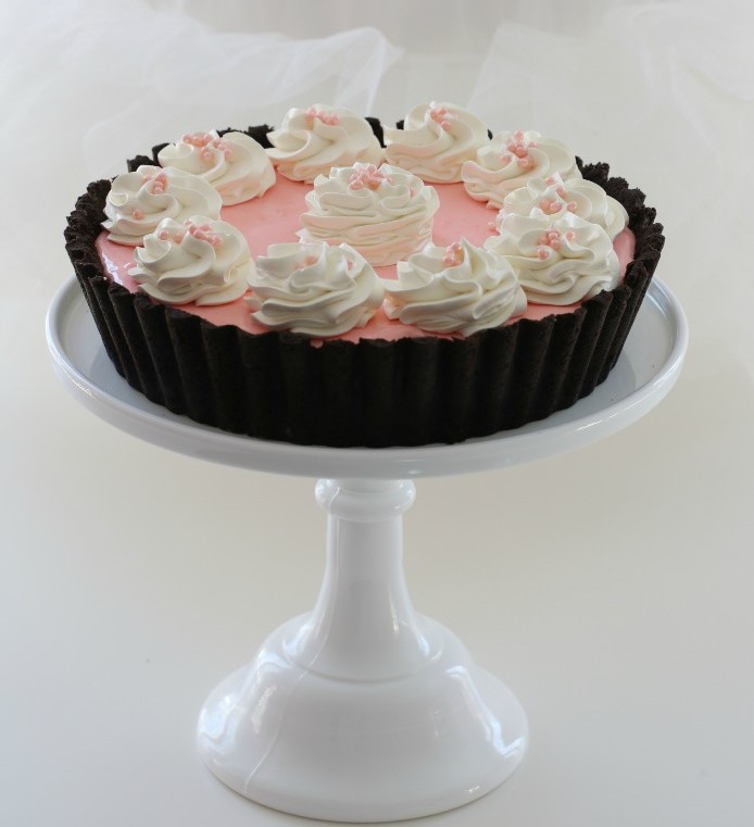 Tarte rosa com chantilly branco em suporte branco