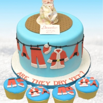 Bolo azul com decoração de roupas de pai natal penduradas e figura de homem de barba branca no topo