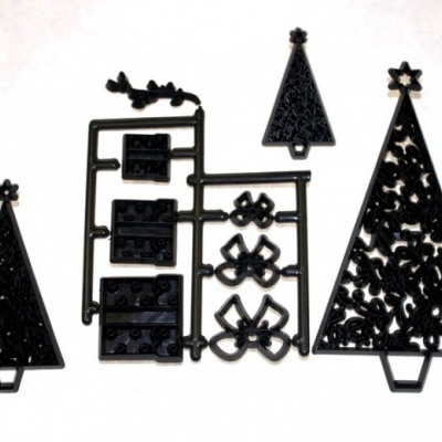 Peças de plástico preto para montagem, incluindo árvores de Natal e ornamentos.