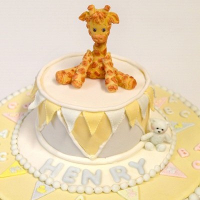 Bolo decorado com girafa, ursinho, nome e bandeirolas coloridas