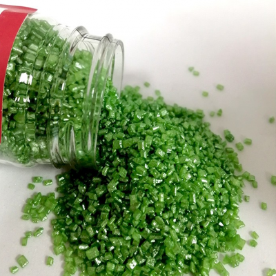 Pequenos cristais verdes translúcidos espalhados de frasco de vidro aberto