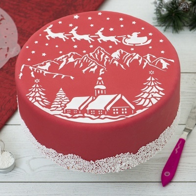 Bolo redondo vermelho com decoração branca de Natal e confeitos na base