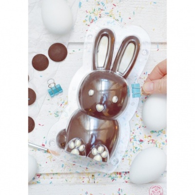 Figura de chocolate em forma de coelho com detalhes brancos, ovos e confeitos coloridos