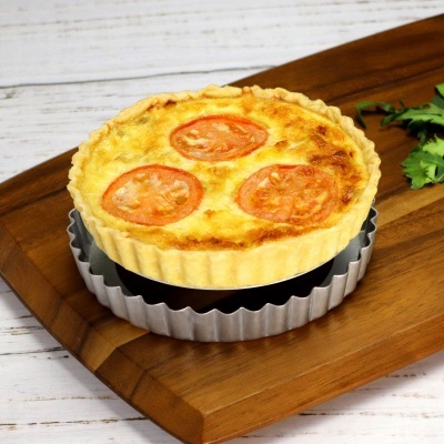 Tarte salgada com tomate e queijo num tabuleiro de madeira