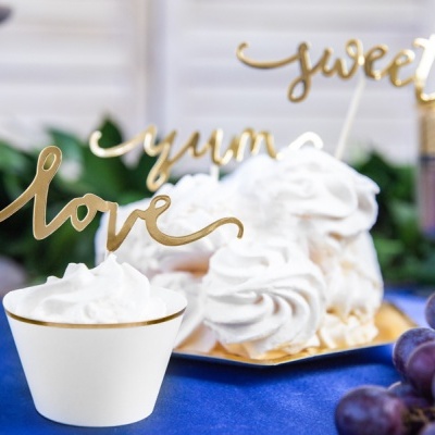 Sobremesas brancas cremosas com decorações douradas em toalha azul