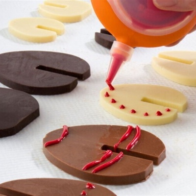 Peças de chocolate branco e preto com glacê vermelho a ser aplicado