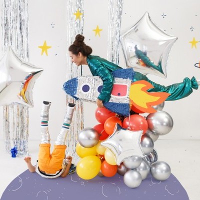 Crianças com fatos brilhantes e balões coloridos em decoração espacial